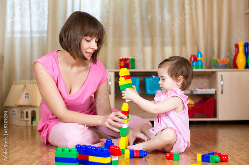 Photo: Happy mother and kid play with toys at home interior Happy mother and kid play with toys at home interior