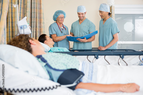 Photo: Nurses Examining Patient's Report Nurses Examining Patient's Report
