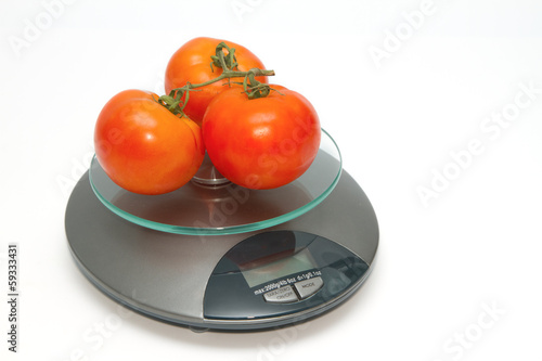 Photo: fresh tomato on weight scales fresh tomato on weight scales