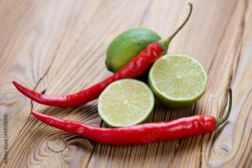 Photo: Red chili peppers and ripe limes on a rustic wooden table Red chili peppers and ripe limes on a rustic wooden table