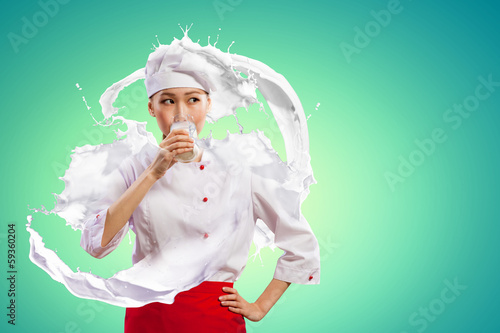 Photo: Asian female cook against milk splashes Asian female cook against milk splashes