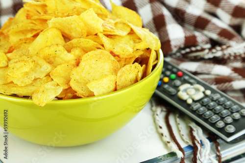 Photo: Chips in bowl, magazines, plaid and TV remote close-up Chips in bowl, magazines, plaid and TV remote close-up