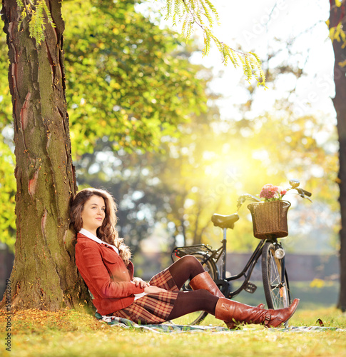Photo: Young beautiful female with bicycle relaxing on a sunny day Young beautiful female with bicycle relaxing on a sunny day