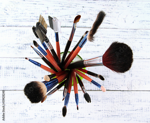 Photo: Makeup brushes in glass on wooden background Makeup brushes in glass on wooden background