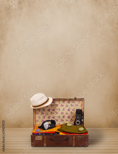 Photo: Retro tourist luggage with colorful clothes and copyspace Retro tourist luggage with colorful clothes and copyspace