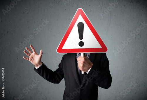 Photo: Businessman holding an exclamation road sign Businessman holding an exclamation road sign