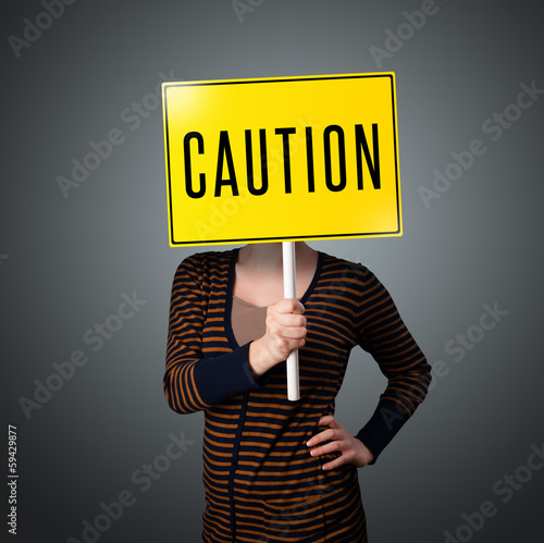 Photo: Young woman holding a caution sign Young woman holding a caution sign