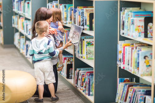 Photo: Teacher With Children Selecting Book In Library Teacher With Children Selecting Book In Library
