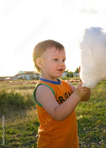 Photo: Adorable little boy enjoying cotton candy Adorable little boy enjoying cotton candy