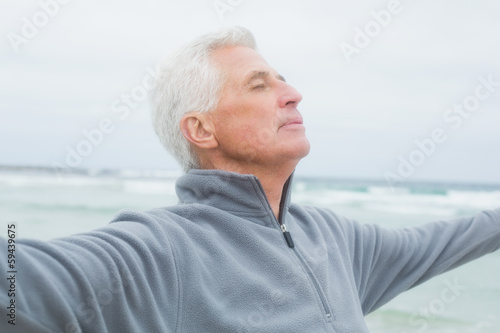 Photo: Senior man with arms outstretched at beach Senior man with arms outstretched at beach