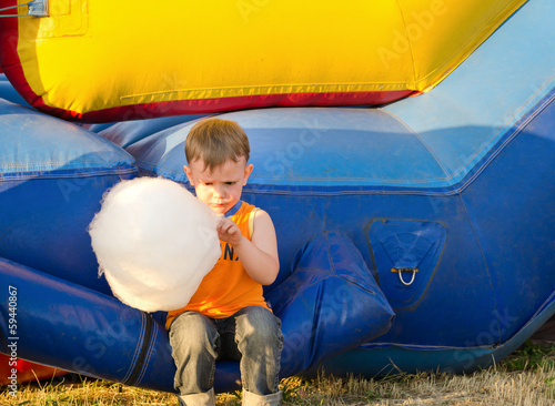 Photo: Cute small boy enjoying a stick of candy floss Cute small boy enjoying a stick of candy floss
