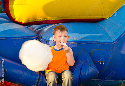 Photo: Cute small boy enjoying a stick of candy floss Cute small boy enjoying a stick of candy floss