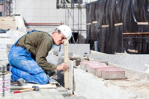 Photo: Worker with level examining marble tiles installation Worker with level examining marble tiles installation