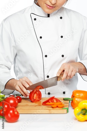 Photo: Beautiful young woman cook cutting fresh tomatoes Beautiful young woman cook cutting fresh tomatoes