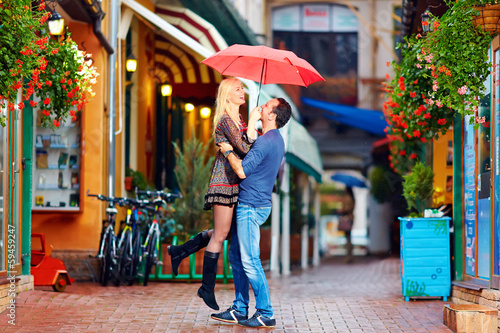 Photo: happy couple in love embracing on colorful street happy couple in love embracing on colorful street