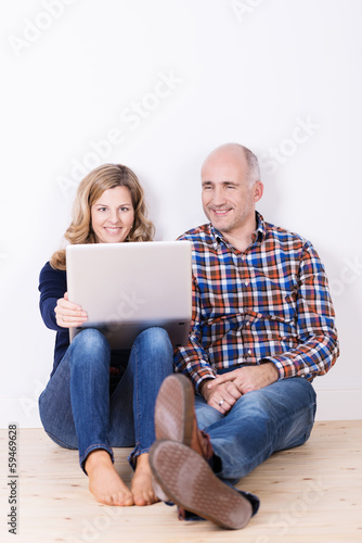 Photo: ehepaar sitzt mit laptop auf dem fußboden ehepaar sitzt mit laptop auf dem fußboden