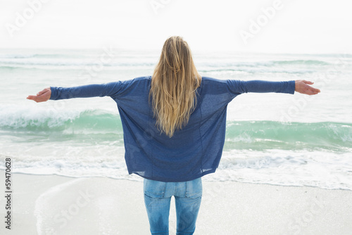 Photo: Rear view of a blond with arms outstretched at beach Rear view of a blond with arms outstretched at beach