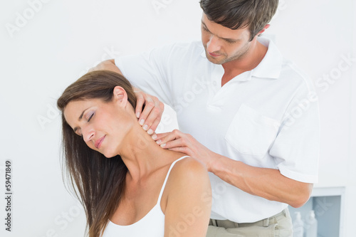Photo: Male chiropractor massaging a young woman's neck Male chiropractor massaging a young woman's neck
