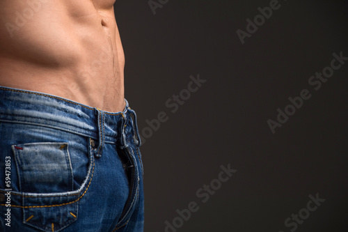 Photo: Close up of muscular male abdomen and blue jeans. Close up of muscular male abdomen and blue jeans.