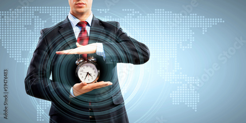 Photo: Business man holding alarmclock Business man holding alarmclock