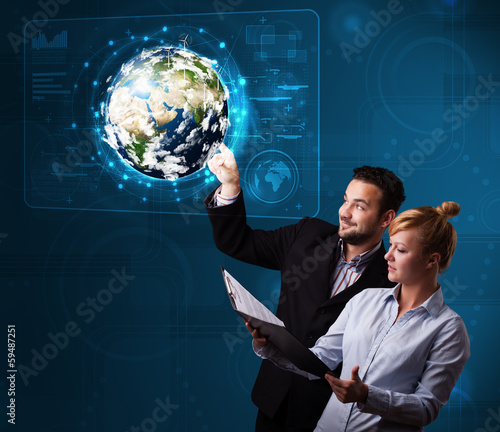Photo: Young couple touching high-tech 3d earth panel Young couple touching high-tech 3d earth panel
