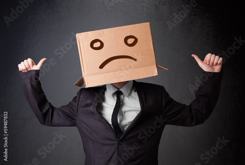 Photo: Businessman gesturing with cardboard box on his head with sad fa Businessman gesturing with cardboard box on his head with sad fa