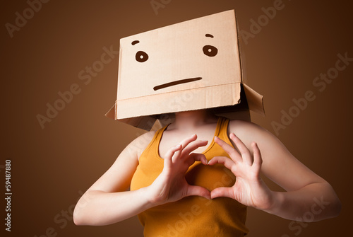 Photo: Young girl gesturing with a cardboard box on her head with strai Young girl gesturing with a cardboard box on her head with strai