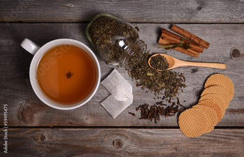 Photo: Cup of green tea, cinnamon and cookies on wooden background Cup of green tea, cinnamon and cookies on wooden background