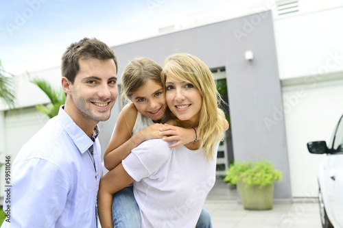 Photo: Parents with kid standing in front of new home Parents with kid standing in front of new home