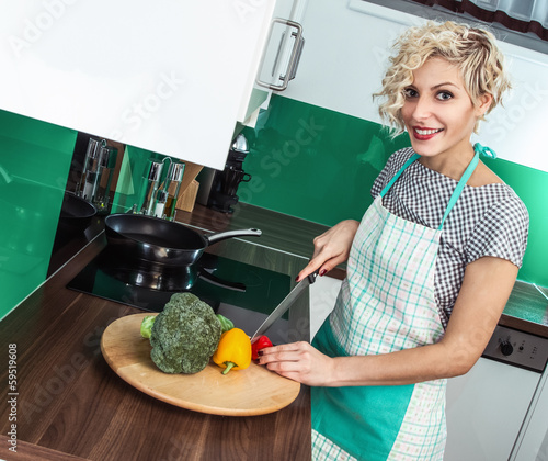 Photo: Smiling woman cooking healthy food at home Smiling woman cooking healthy food at home