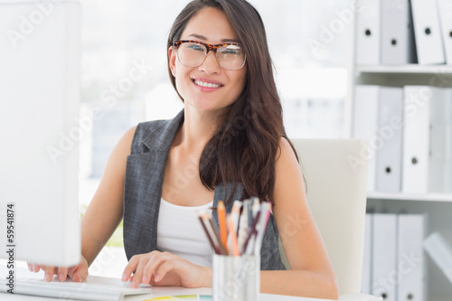 Photo: Portrait of a smiling young woman using computer Portrait of a smiling young woman using computer