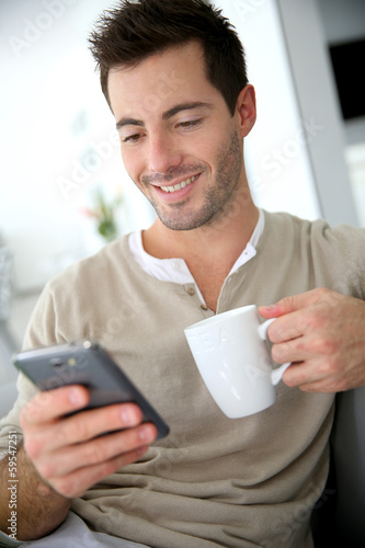 Photo: Man at home connected on smartphone Man at home connected on smartphone