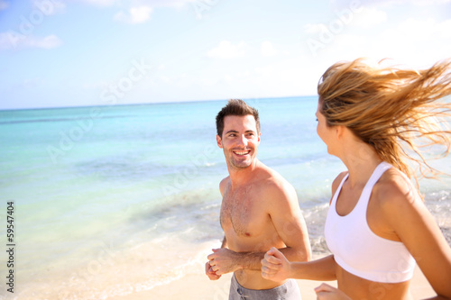 Photo: Cheerful couple training on the beach Cheerful couple training on the beach