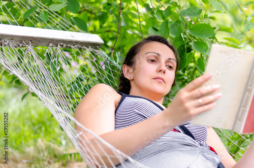 Photo: Woman reading whilst relaxing in a hammock Woman reading whilst relaxing in a hammock