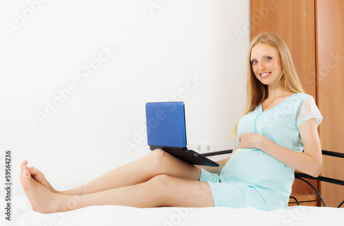 Photo: pregnancy woman with laptop on white sheet pregnancy woman with laptop on white sheet
