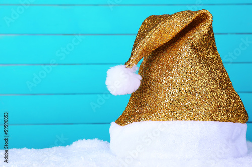 Photo: Santa hat on snow on color wooden background Santa hat on snow on color wooden background