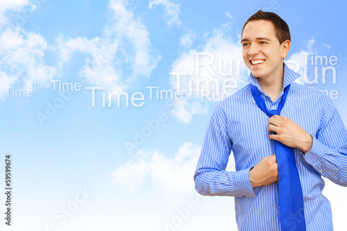 Photo: Young business man binding his blue tie Young business man binding his blue tie