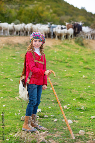 Photo: Kid girl shepherdess happy with flock of sheep and stick Kid girl shepherdess happy with flock of sheep and stick
