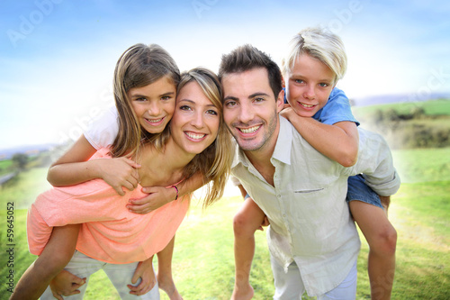 Photo: Parents giving piggyback ride to kids Parents giving piggyback ride to kids