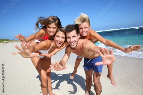 Photo: Parents giving piggyback ride to kids at the beach Parents giving piggyback ride to kids at the beach