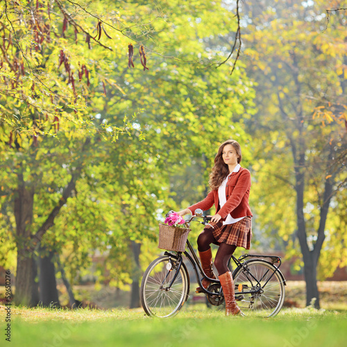 Photo: Beautiful female on a bicycle in a park looking at camera Beautiful female on a bicycle in a park looking at camera