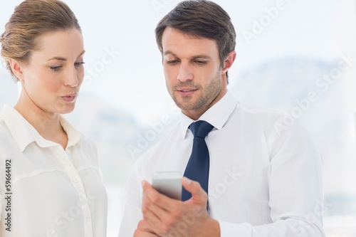 Photo: Smartly dressed colleagues looking at mobile phone Smartly dressed colleagues looking at mobile phone