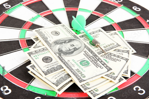 Photo: Dart on dartboard and money close up. Concept of success. Dart on dartboard and money close up. Concept of success.