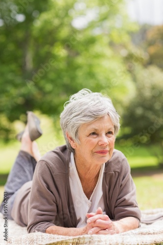 Photo: Thoughtful senior woman lying at park Thoughtful senior woman lying at park