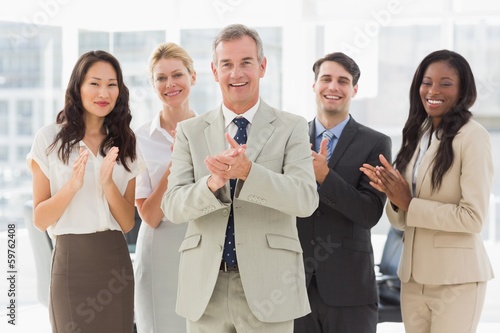Photo: Business team standing and clapping at the camera Business team standing and clapping at the camera