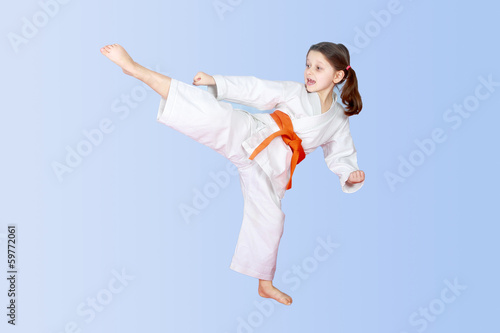 Photo: On a light background little athlete beat high leg kick On a light background little athlete beat high leg kick