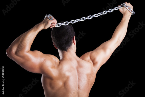 Photo: Muscular young man from back on black background Muscular young man from back on black background