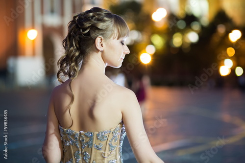Photo: Young girl in a beautiful dress stands back Young girl in a beautiful dress stands back