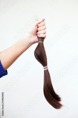 Photo: hand holding cut off ponytail of hair hand holding cut off ponytail of hair