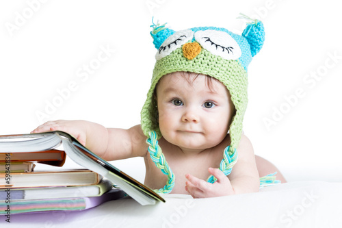 Photo: baby in funny knitted hat owl with books on white background baby in funny knitted hat owl with books on white background